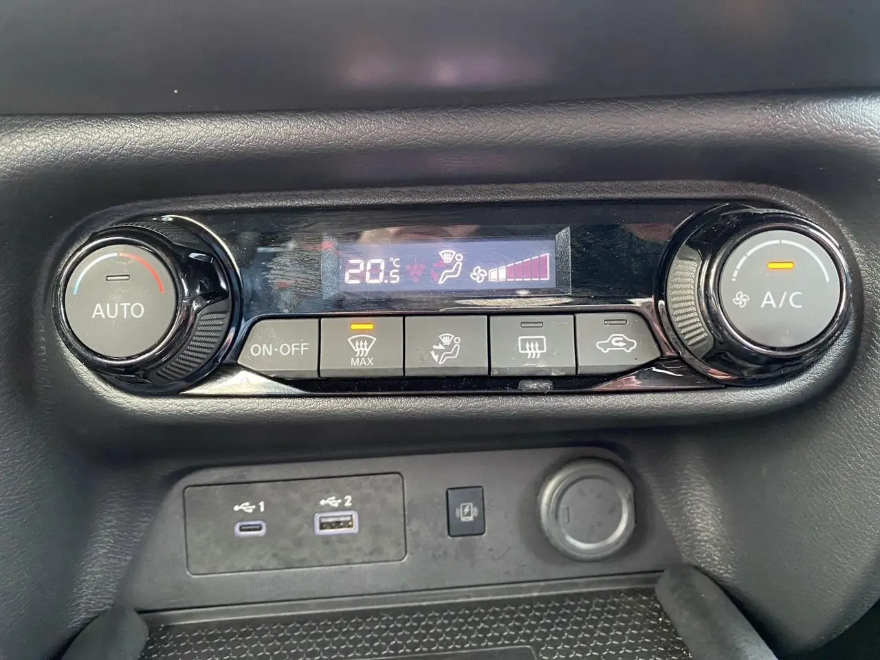Gros plan sur la commande de climatisation automatique et ports USB du Nissan Juke 2025, intérieur noir.