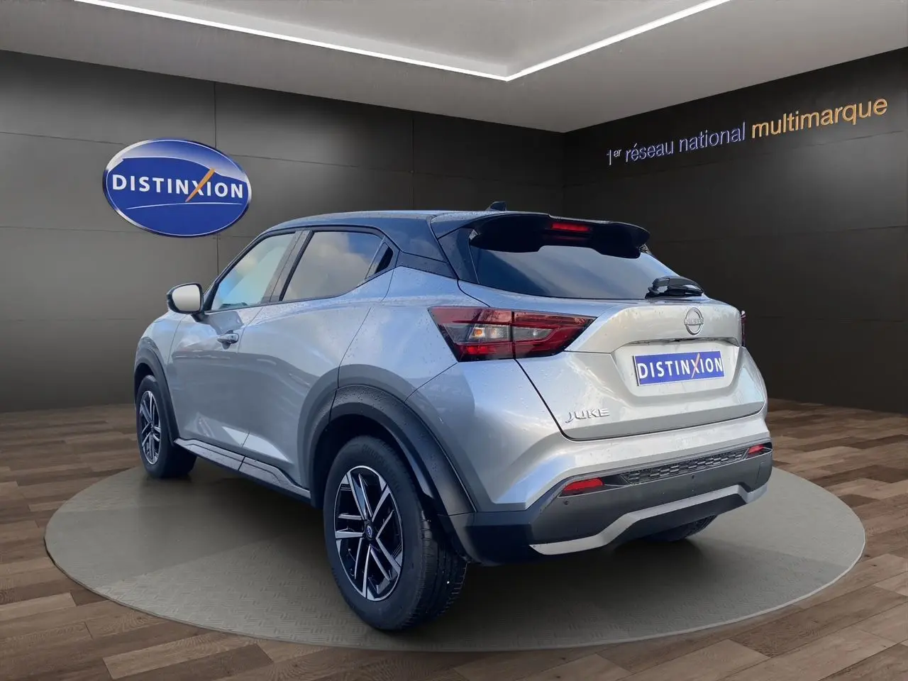 Nissan Juke 2025 gris perle avec toit noir, vue 3/4 arrière droit, jantes alliage 17 pouces et feux LED.