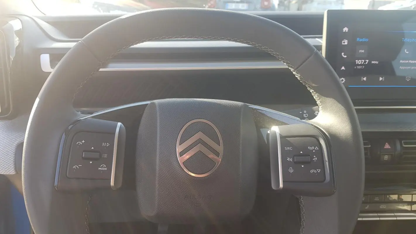 Vue rapprochée du volant noir de la Citroën C3 2024 avec commandes intégrées et tableau de bord numérique.