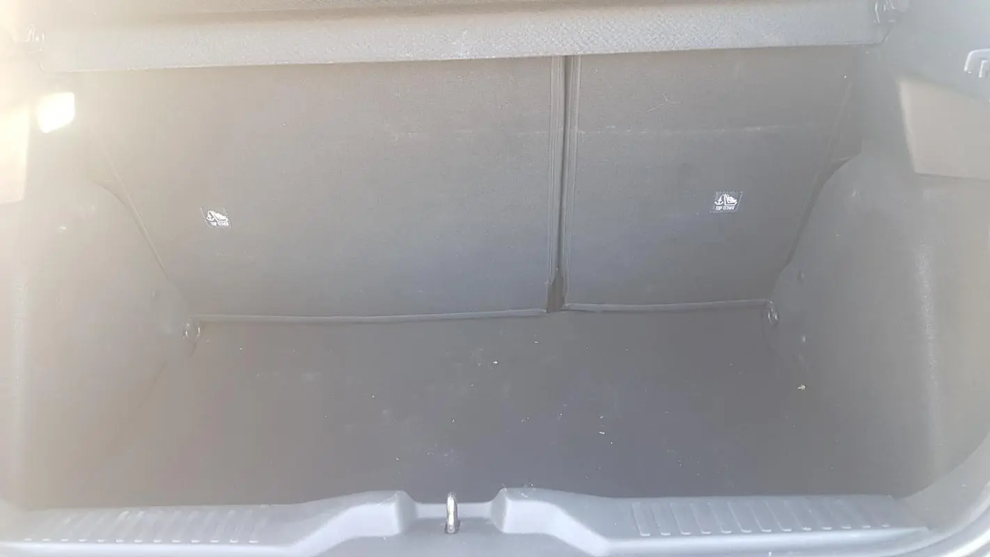 Vue intérieure du coffre vide d'une Citroën C3 2024 bleu foncé, montrant le revêtement noir et les fixations ISOFIX.