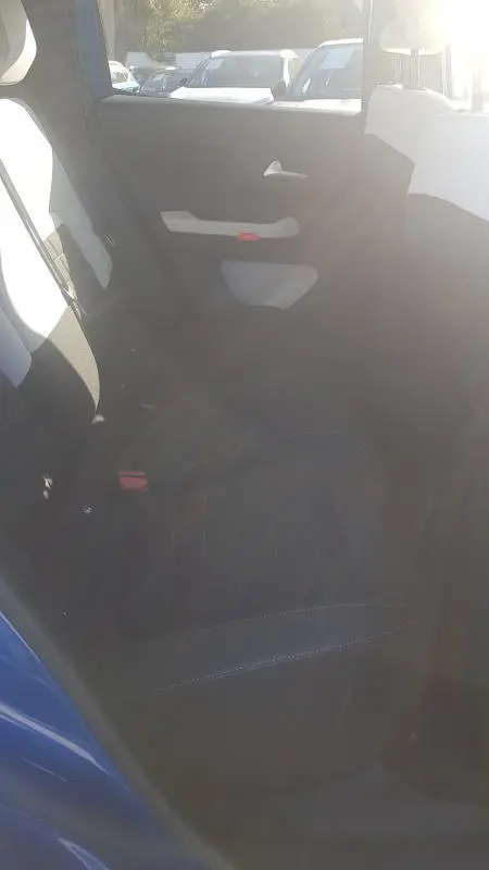 Vue intérieure arrière côté gauche de la Citroën C3 bleu foncé, montrant la banquette et la portière avec poignée blanche.