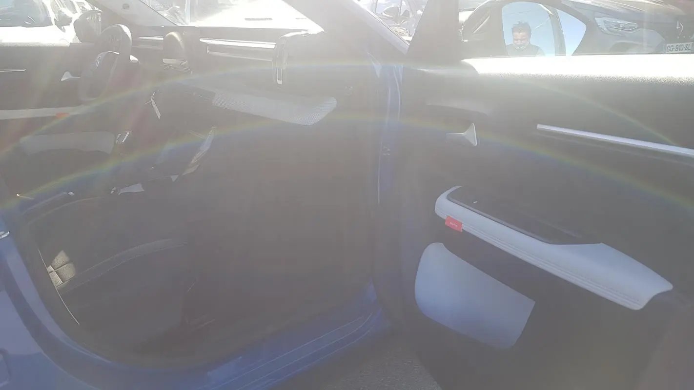 Intérieur de la Citroën C3 bleu foncé 2024 vu côté passager, avec porte ouverte et sellerie noire.