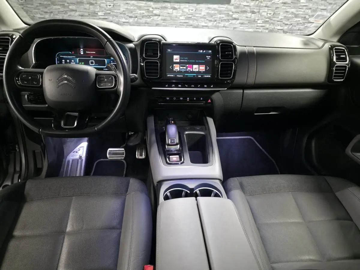 Vue intérieure avant du Citroën C5 Aircross gris, avec tableau de bord numérique et console centrale moderne.