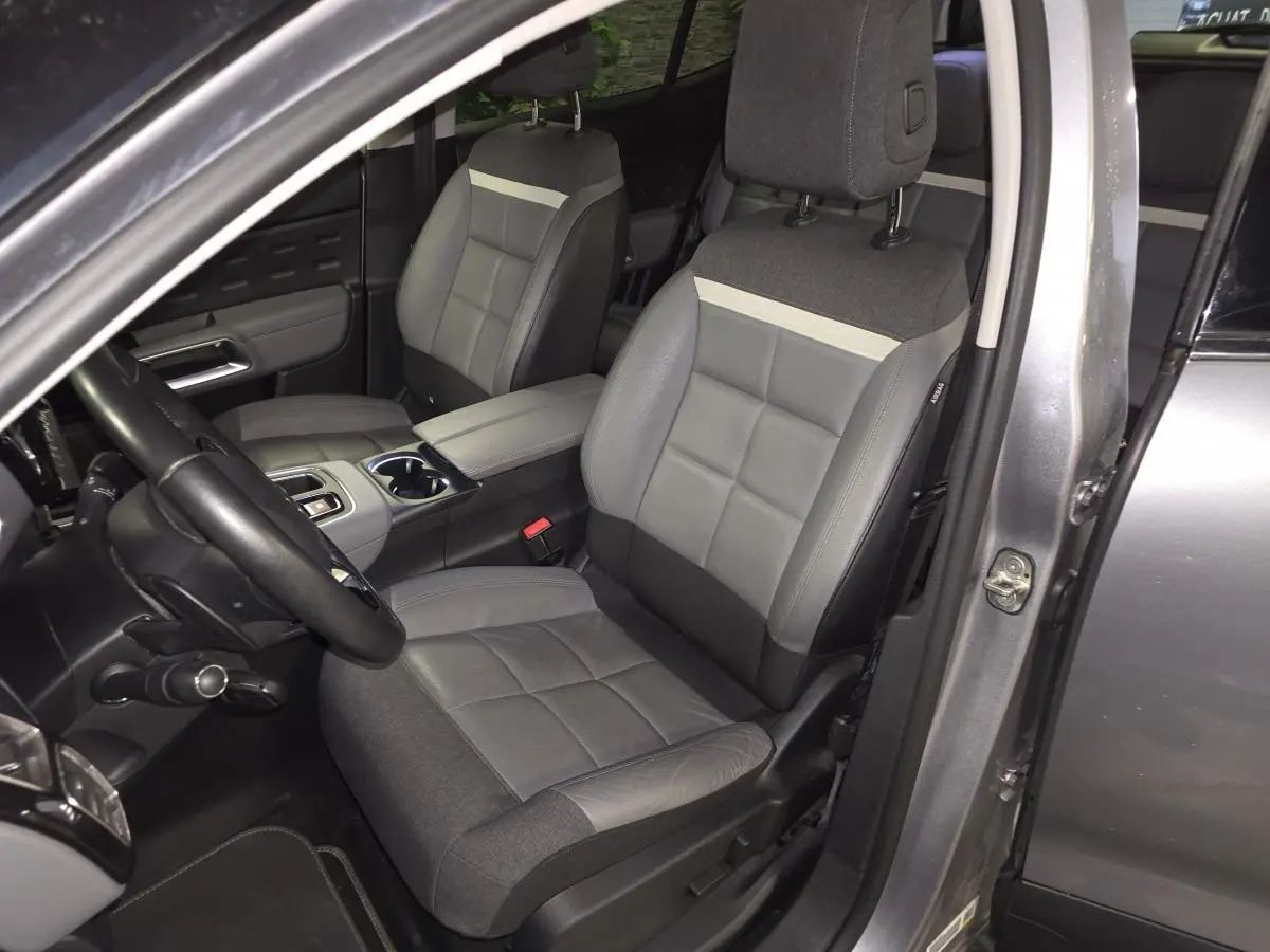 Vue intérieure côté conducteur du Citroën C5 Aircross gris, sièges cuir grainé et tissu gris avec console centrale ouverte.