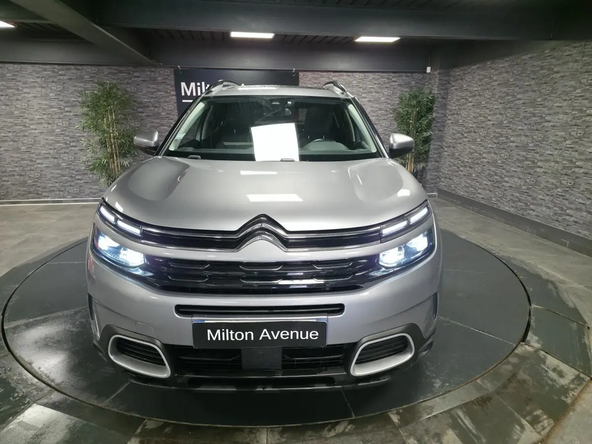 Vue avant d'un Citroën C5 Aircross gris acier avec feux LED allumés dans un showroom.