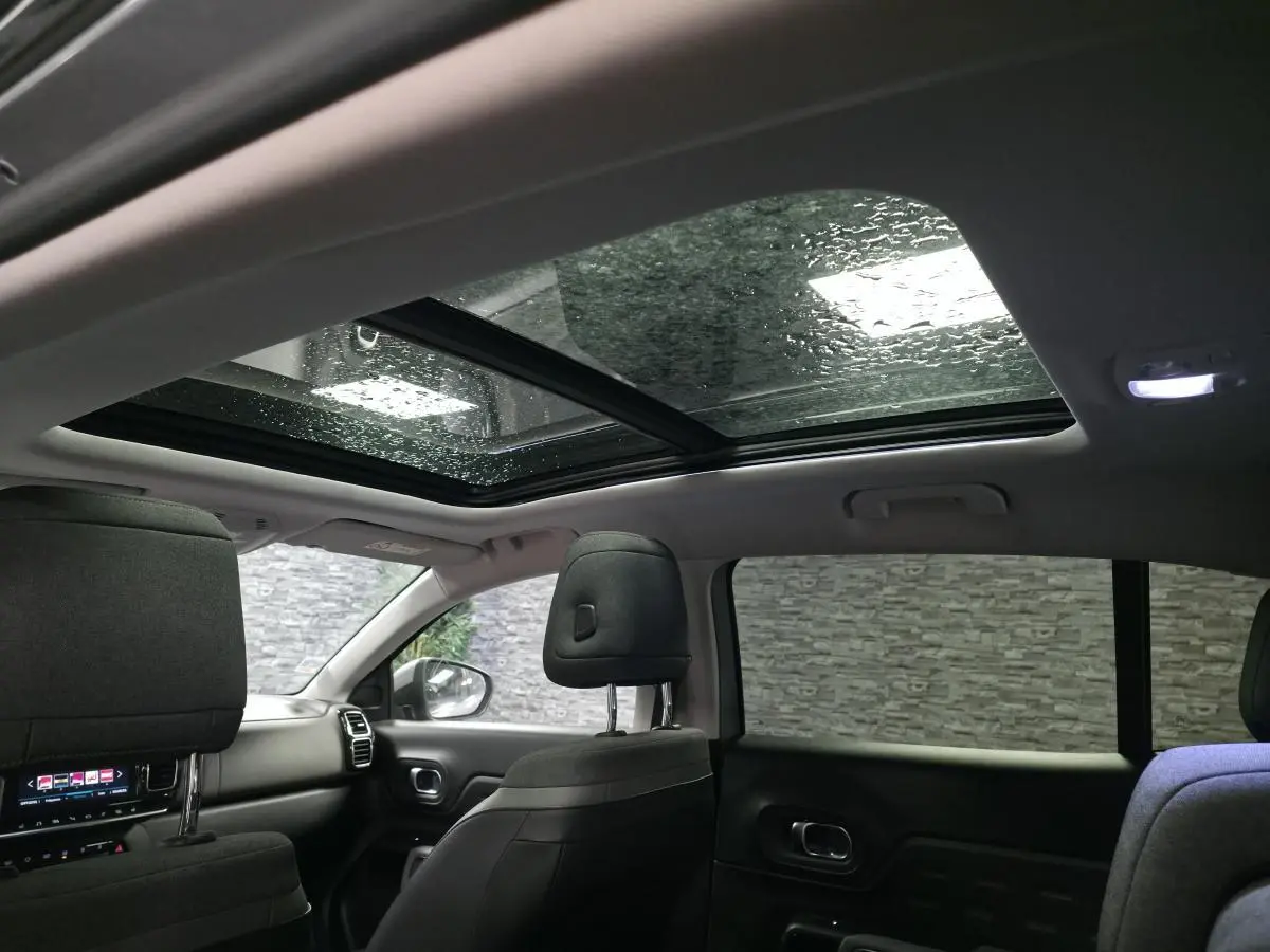 Vue intérieure arrière du Citroën C5 Aircross 2019, toit ouvrant panoramique et sièges en cuir gris visibles.