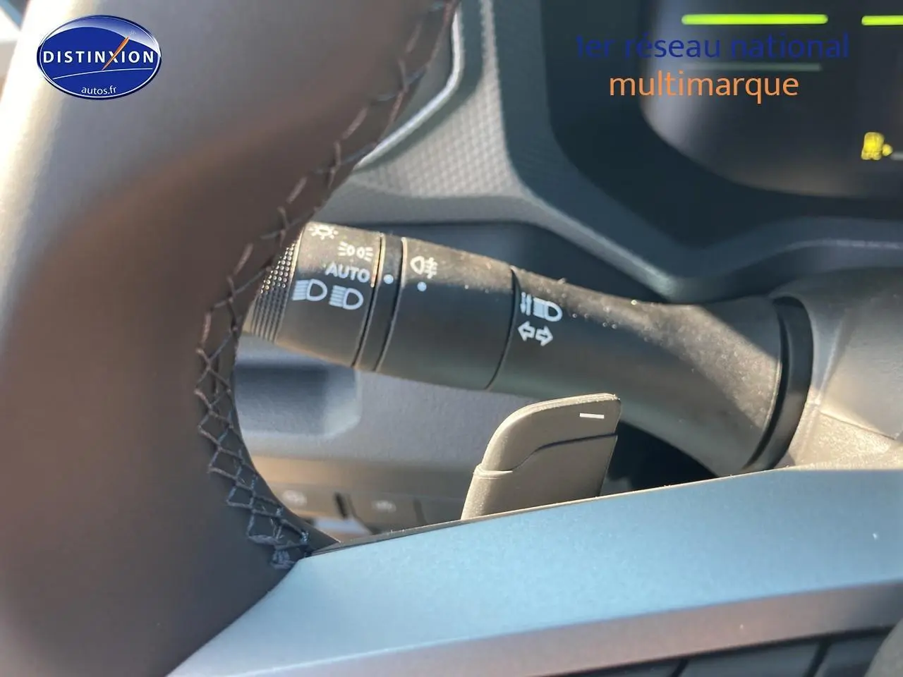 Gros plan sur le commodo des feux et la palette de changement de vitesse derrière le volant d’un Dacia Duster kaki lichen.