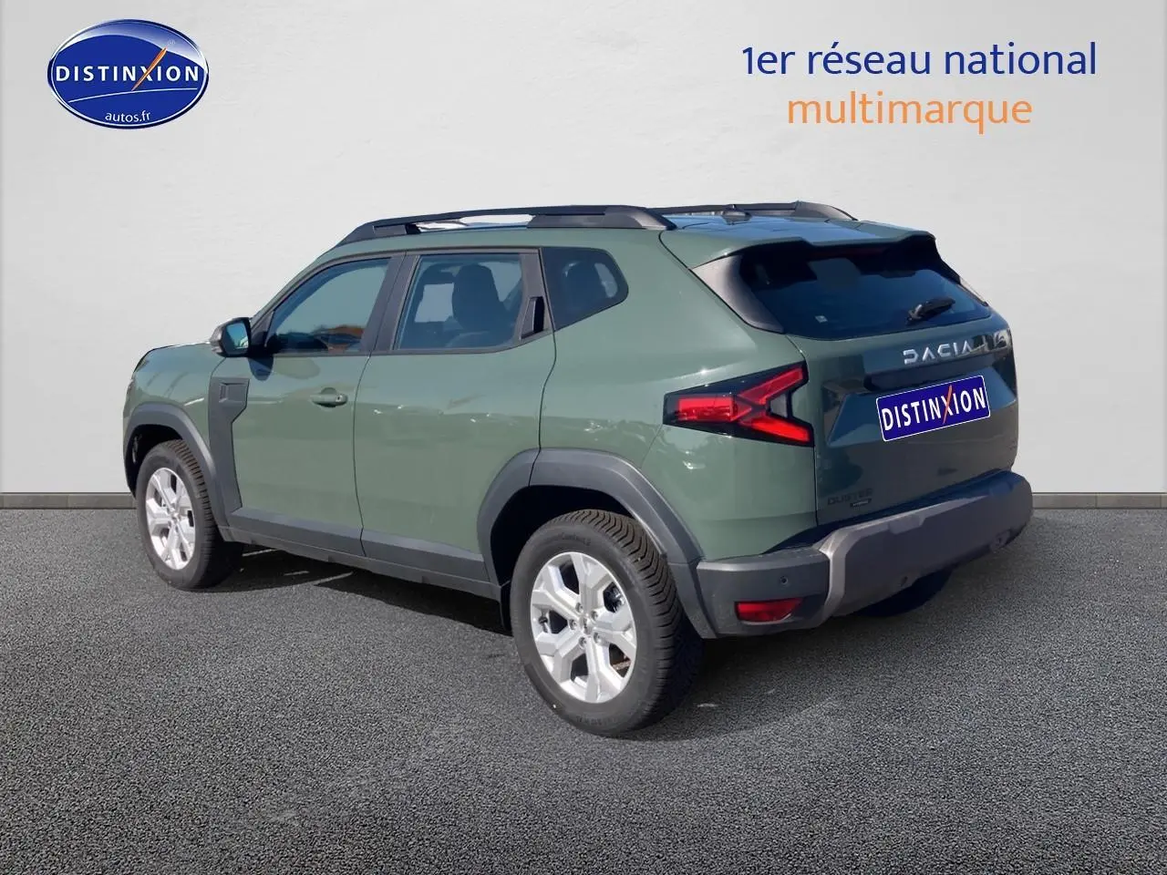 Vue 3/4 arrière droite d'un Dacia Duster 2026 kaki lichen avec barres de toit et jantes alu visibles.