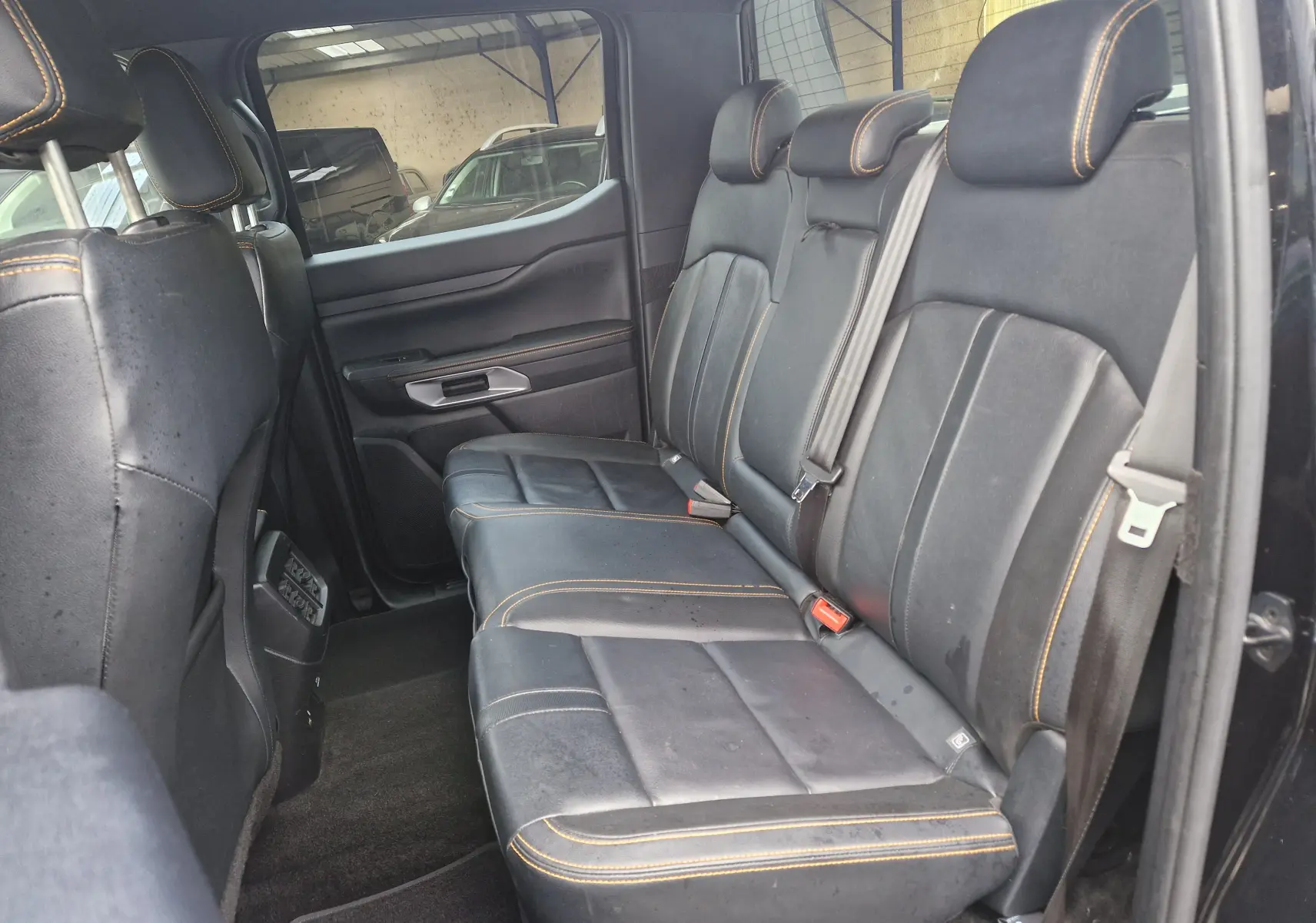 Vue intérieure côté droit des sièges arrière en cuir noir avec surpiqûres orange du Ford Ranger Double Cabine 2023.