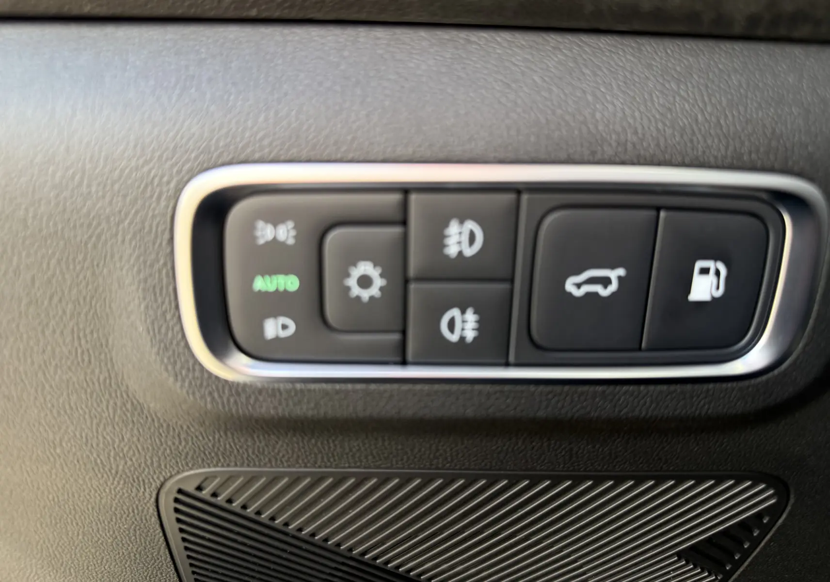 Gros plan sur les boutons de commande d’éclairage et d’ouverture du coffre dans l’habitacle noir du JAECOO J7 PHEV.