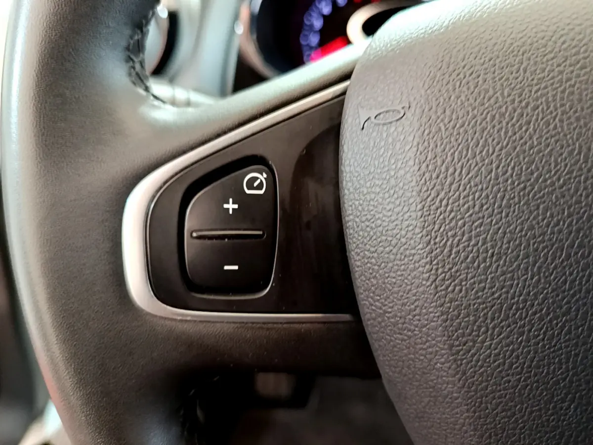 Gros plan sur le volant cuir noir de la Renault Clio Business TCe 90 2019 avec commandes de régulateur de vitesse.