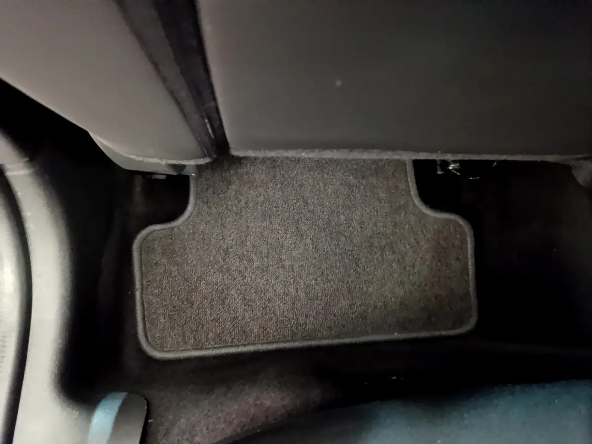 Tapis de sol noir au pied du siège arrière droit d'une Renault Clio Business TCe 90 blanche, vue intérieure rapprochée.