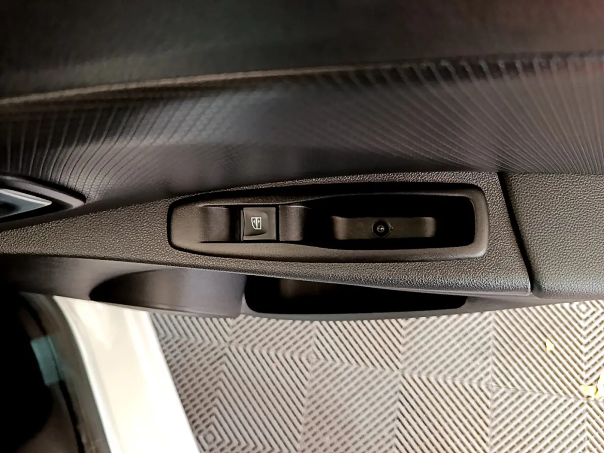 Gros plan sur la commande de lève-vitre côté conducteur d'une Renault Clio Business TCe 90 blanche de 2019.