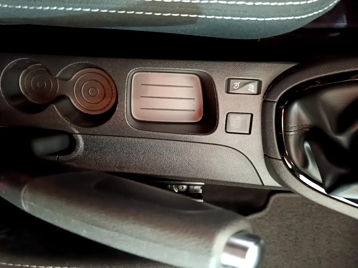 Gros plan sur la console centrale noire de la Renault Clio Business TCe 90 avec frein à main et commandes proches du levier de vitesses.