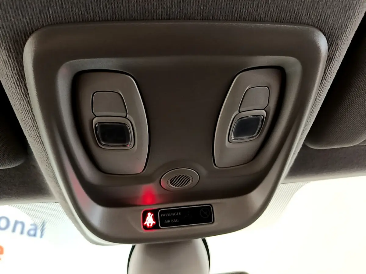 Vue rapprochée du plafonnier gris avec éclairages et témoin airbag passager allumé dans une Renault Clio blanche.