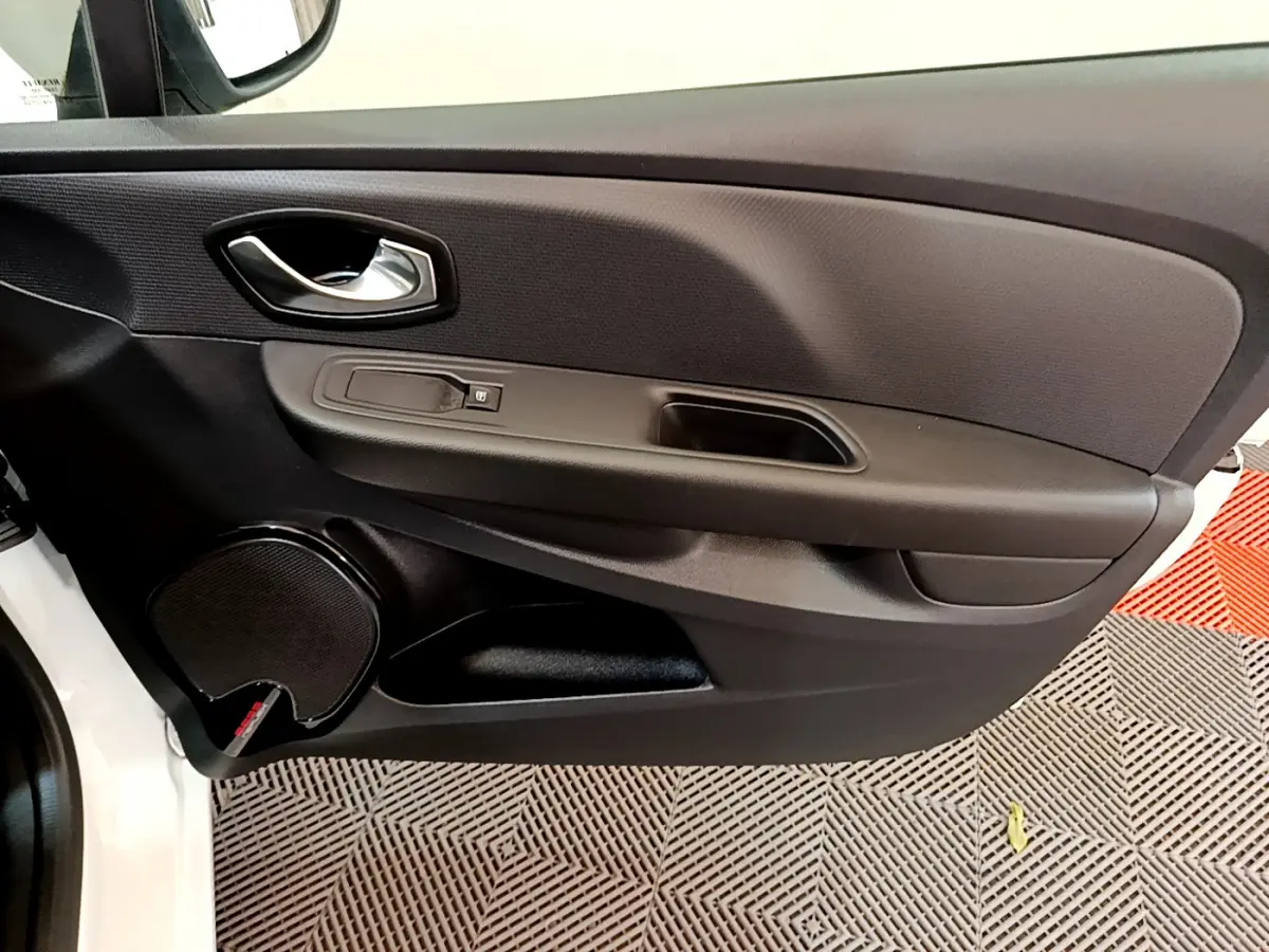 Vue rapprochée de la porte avant gauche noire de la Renault Clio Business TCe 90 blanche, avec poignée et haut-parleur intégrés.