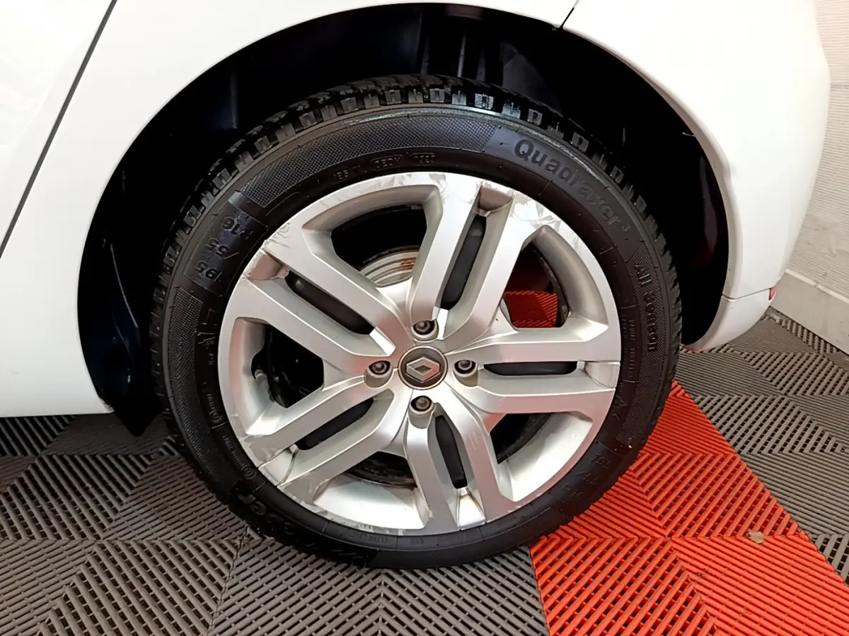 Gros plan sur la roue arrière droite blanche d'une Renault Clio Business TCe 90 avec jante alliage argentée.