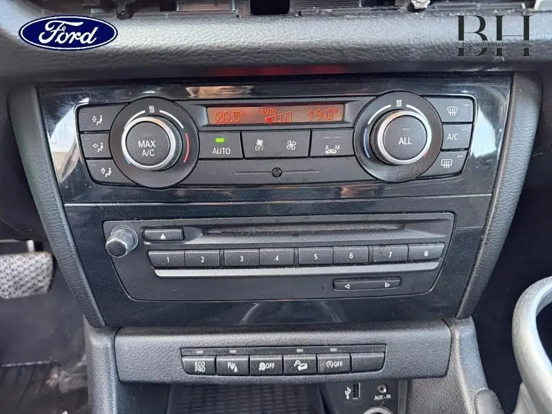 Tableau de bord central de BMW X1 xDrive25dA 2014 avec commandes climatisation et audio en finition Mineralgrau.