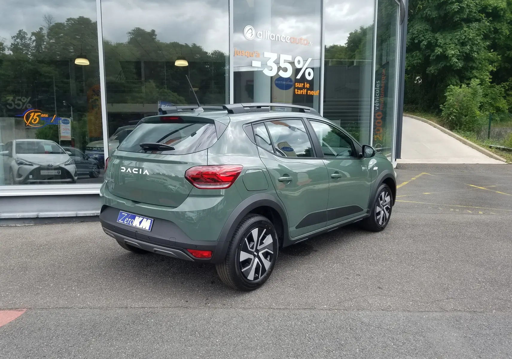 Vue 3/4 arrière droite d'une Dacia Sandero Stepway 2025 en Licken Kaki avec barres de toit et jantes modernes.