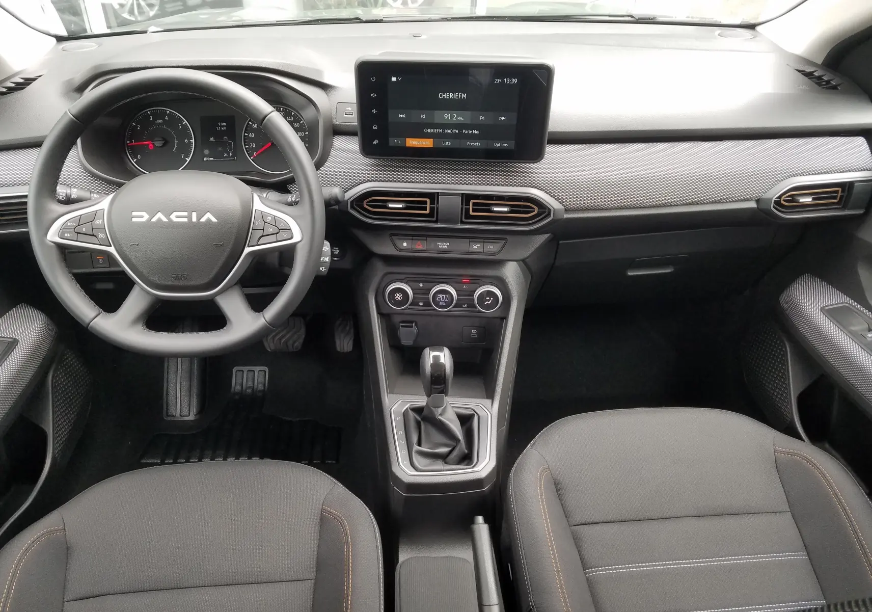 Vue intérieure avant du tableau de bord et volant DACIA Sandero Stepway 2025 avec écran tactile et sellerie noire.