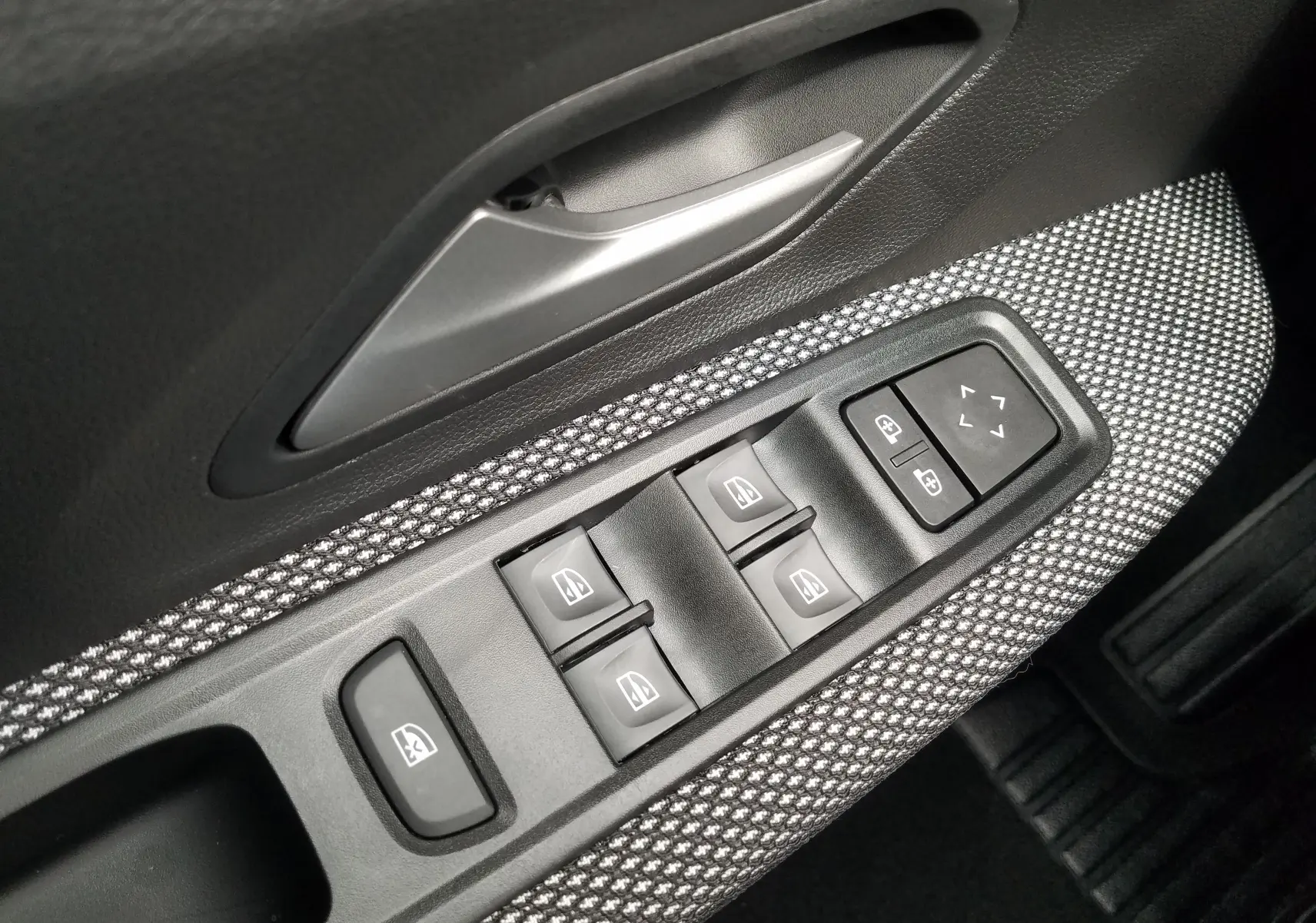 Détail des commandes des vitres et rétroviseurs sur la porte côté conducteur d'une Dacia Sandero Stepway 2025.