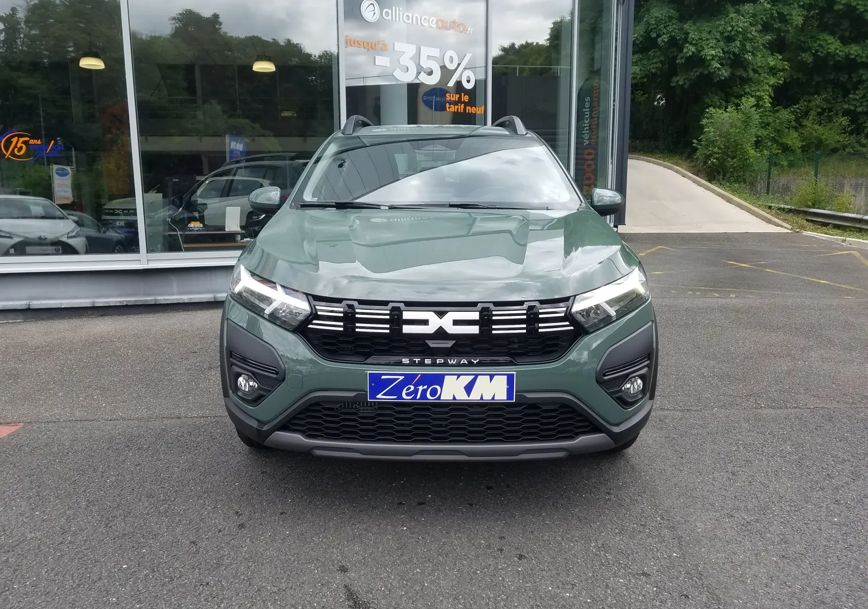 Vue frontale d'une Dacia Sandero Stepway 2025 en Licken Kaki avec calandre noire et feux LED allumés.