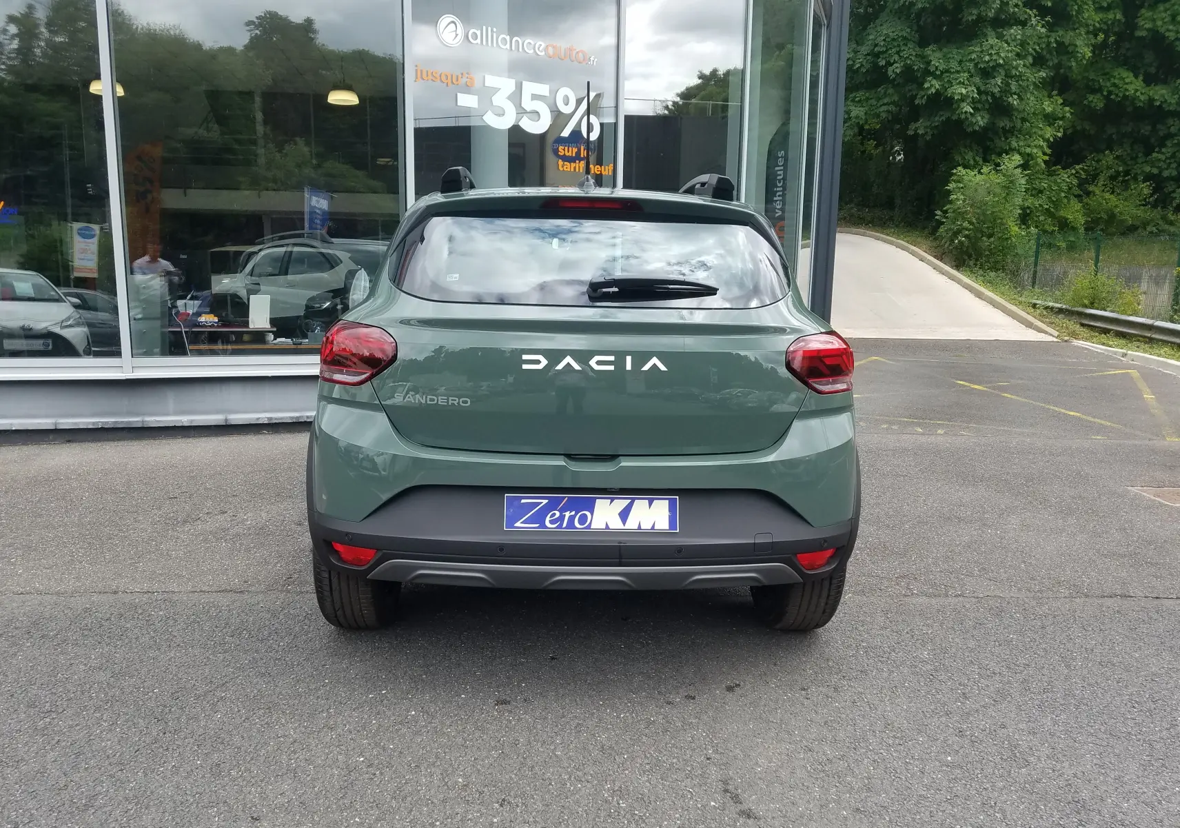 Vue arrière d'une Dacia Sandero Stepway 2025 en vert Licken Kaki avec barres de toit et logo visible.