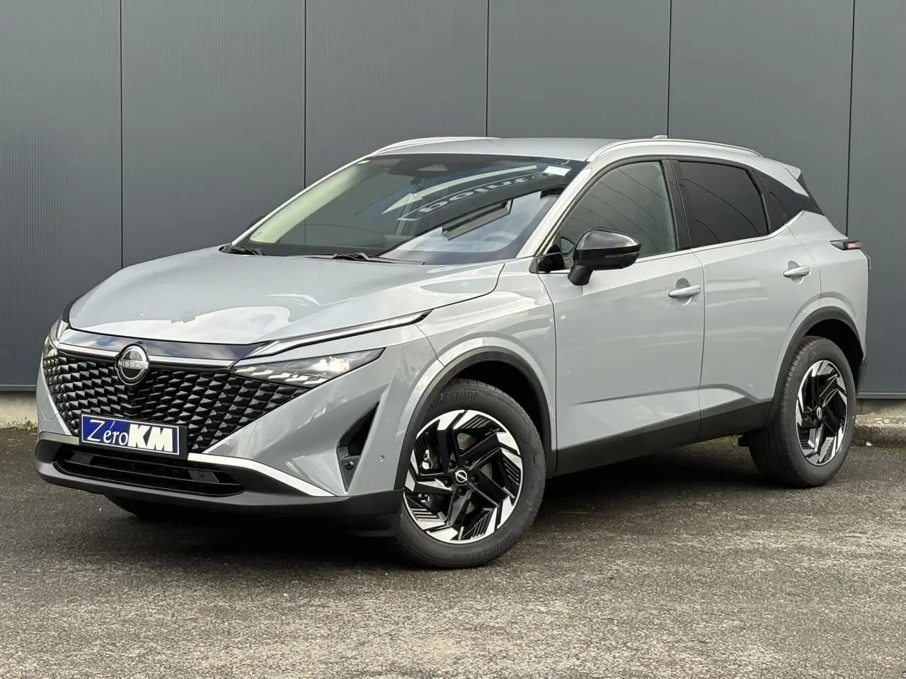 Nissan Qashqai III e-Power gris Ceramic en 3/4 avant droit avec calandre noire et jantes alliage 18 pouces.