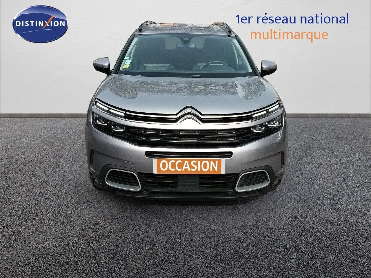 Vue frontale d'un Citroën C5 Aircross gris Artense métal avec calandre distinctive et plaque "OCCASION" visible.