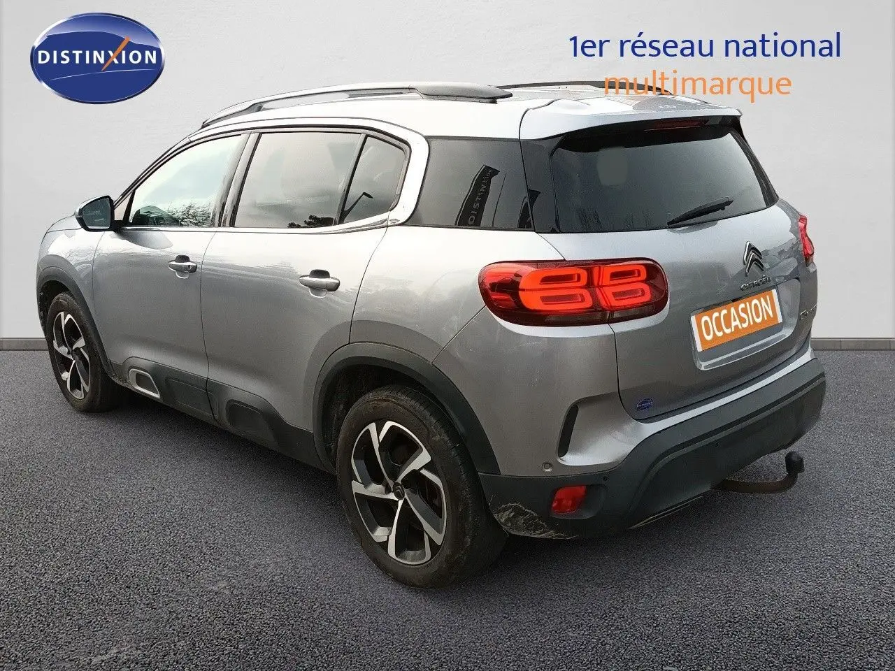 Vue 3/4 arrière droite d'un Citroën C5 Aircross gris Artense métal avec feux arrière LED et attelage visible.