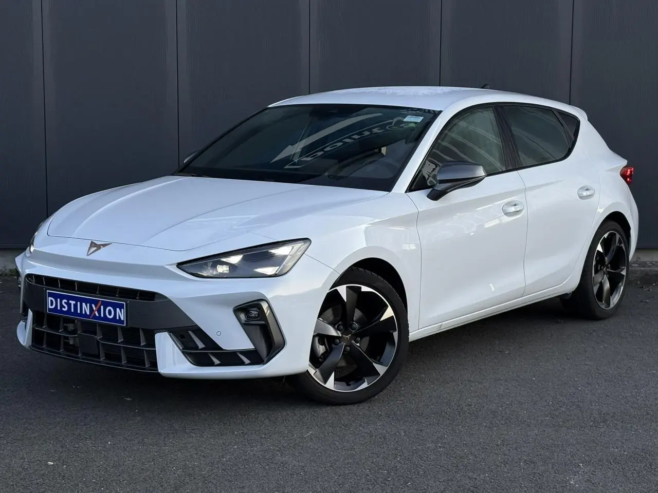 Vue 3/4 avant droite d'une CUPRA Leon blanche Neige avec jantes alliage noires et signature lumineuse Tri-LED.