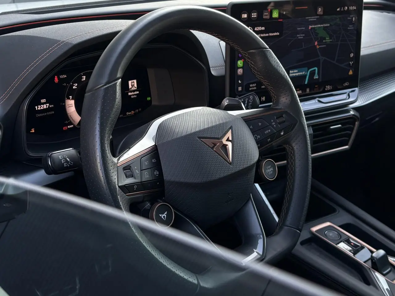 Vue intérieure centrée sur le volant cuir noir perforé et le tableau de bord digital de la CUPRA Leon 2025.