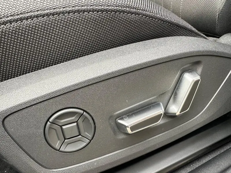 Gros plan sur les commandes de réglage électrique du siège avant en tissu noir de l'Audi Q3 2.0 TDI 150ch S line.
