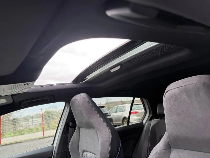 Vue intérieure de la Volkswagen Golf 2.0 TDI R-Line 2026 montrant les sièges avant en tissu gris et le toit ouvrant panoramique.