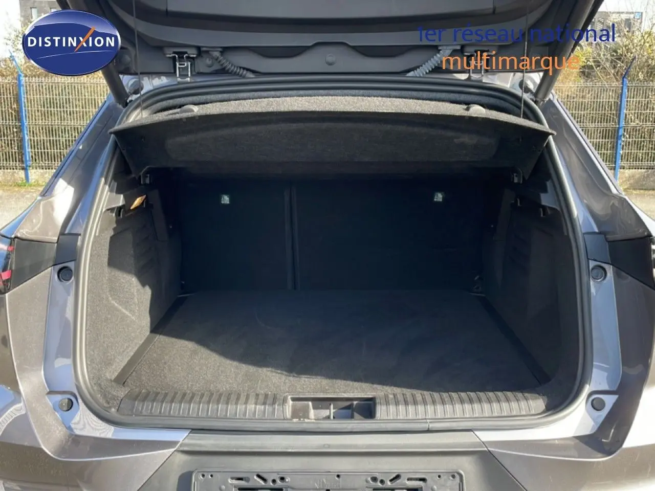 Coffre ouvert vu de l'arrière d'une Renault Symbioz gris cassiopée métal, montrant un espace de chargement vide et spacieux.