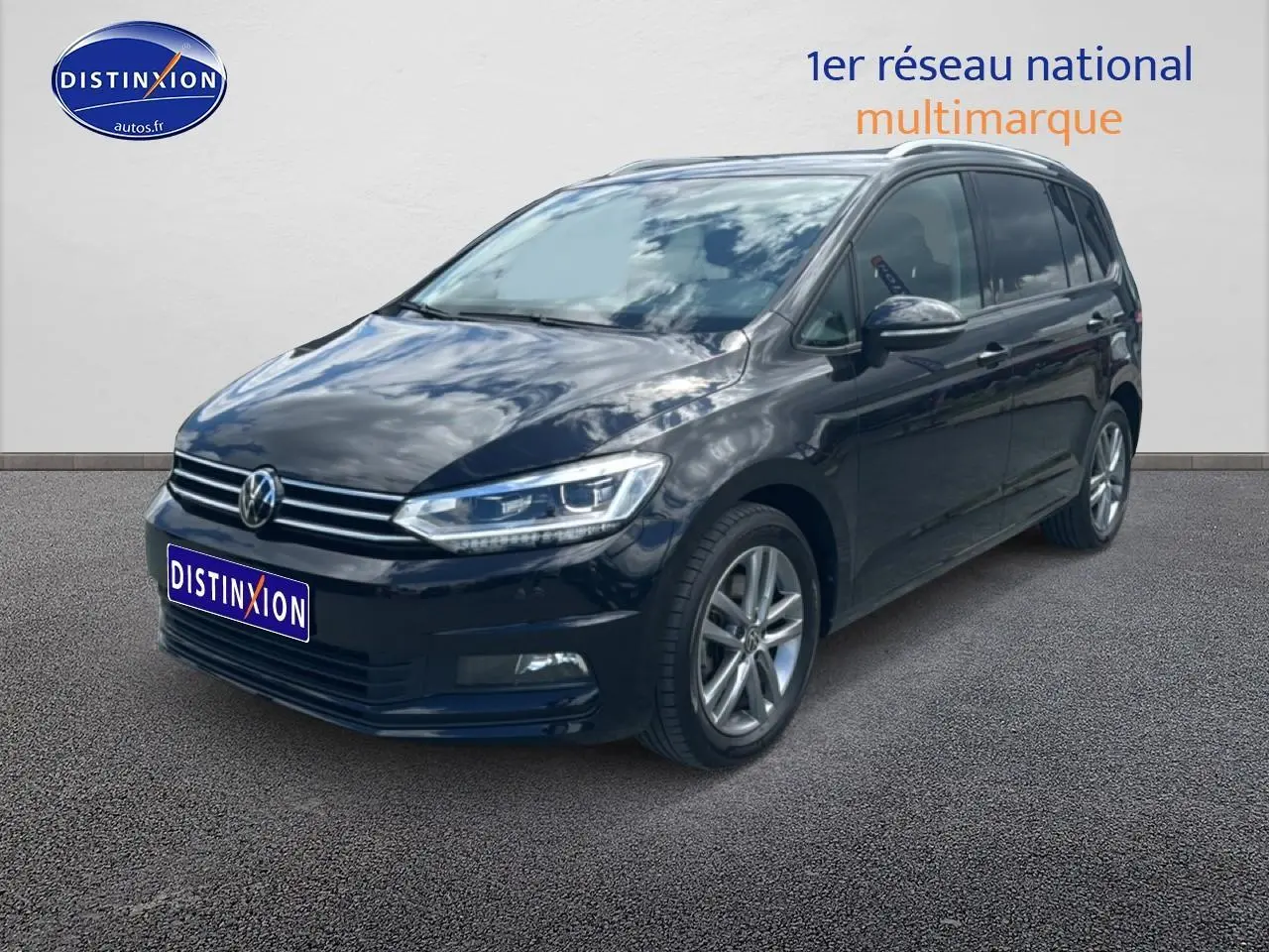 Volkswagen Touran noir vu en 3/4 avant droit, avec calandre chromée et jantes alliage visibles.