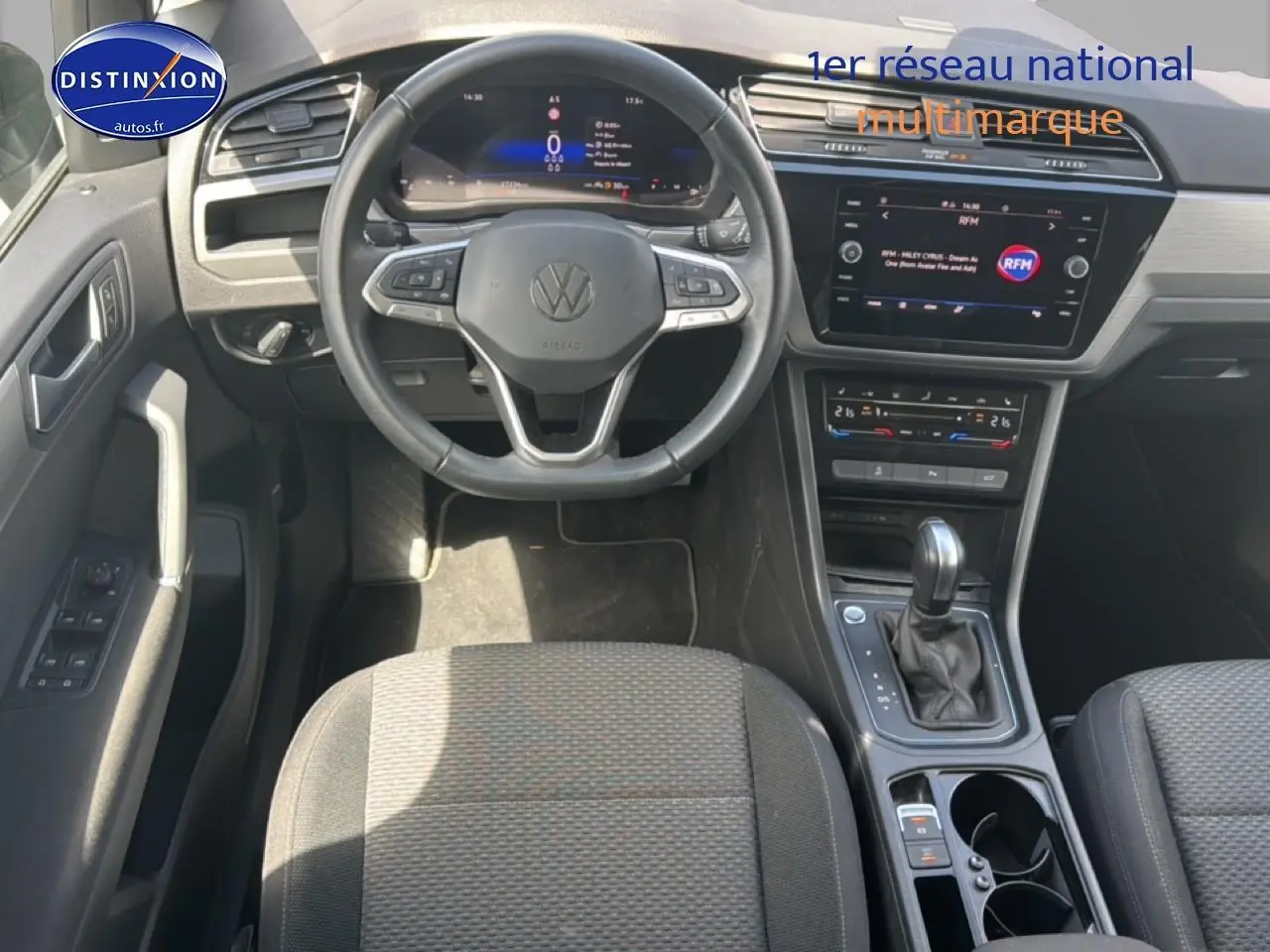 Vue intérieure avant du Volkswagen Touran 2025 noir, volant cuir multifonction et écran tactile central visible.