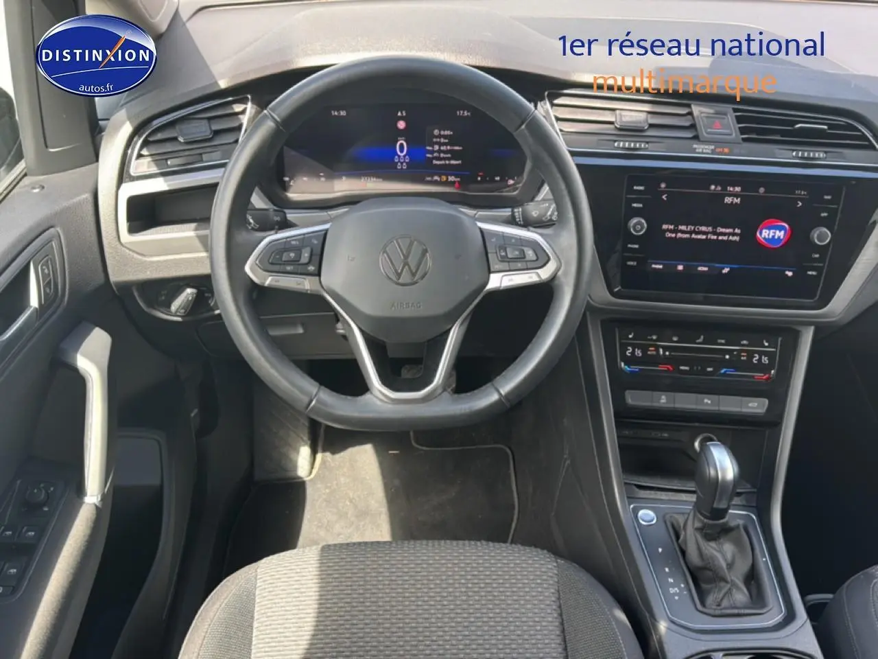 Vue intérieure avant du Volkswagen Touran 2025 noir, montrant le volant cuir multifonction et la console centrale avec écran tactile.