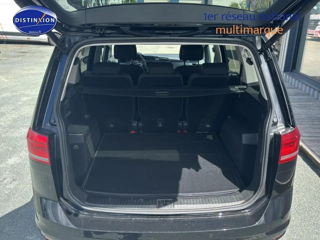 Vue arrière du coffre ouvert d’un Volkswagen Touran noir 2025, montrant la 3ème rangée de sièges et l’espace de chargement.