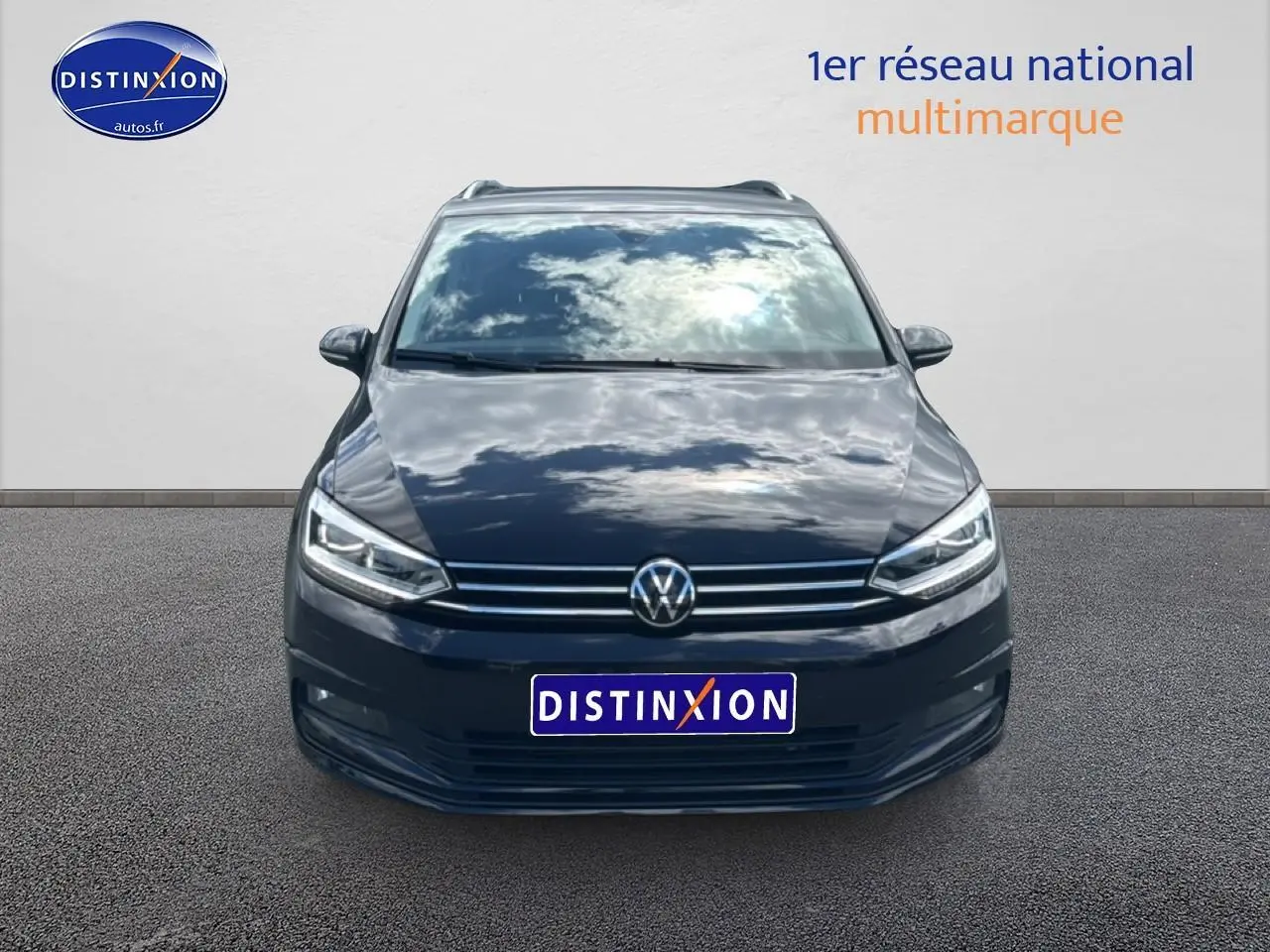 Vue de face du Volkswagen Touran noir 2025 avec calandre chromée et phares LED allumés.