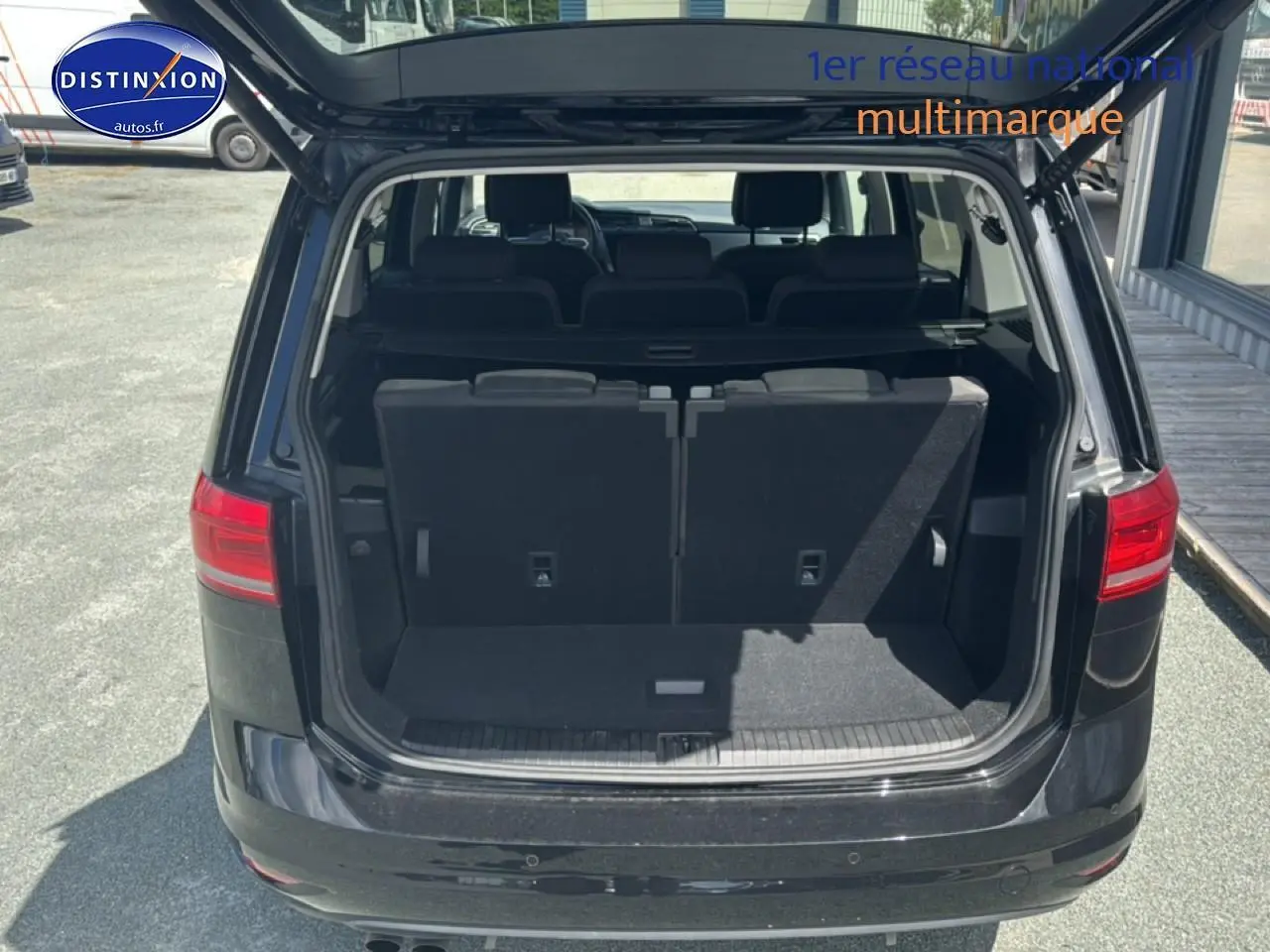 Vue arrière d’un Volkswagen Touran noir 2025 avec coffre ouvert et troisième rangée de sièges visible.