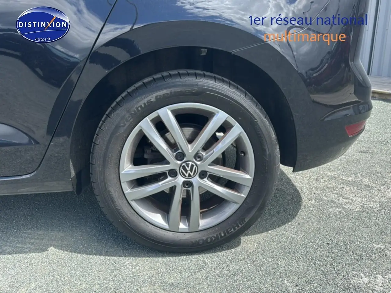 Gros plan sur la roue arrière droite avec jante alu argentée d’un Volkswagen Touran noir.