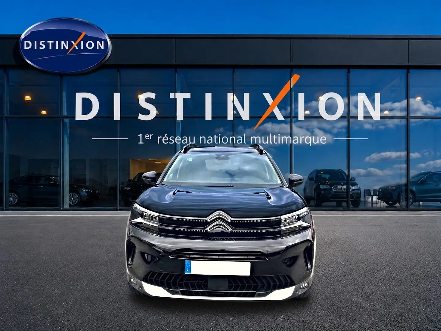 Vue avant d'un Citroën C5 Aircross noir 2025 avec calandre distinctive et phares LED, devant un showroom Distinxion.