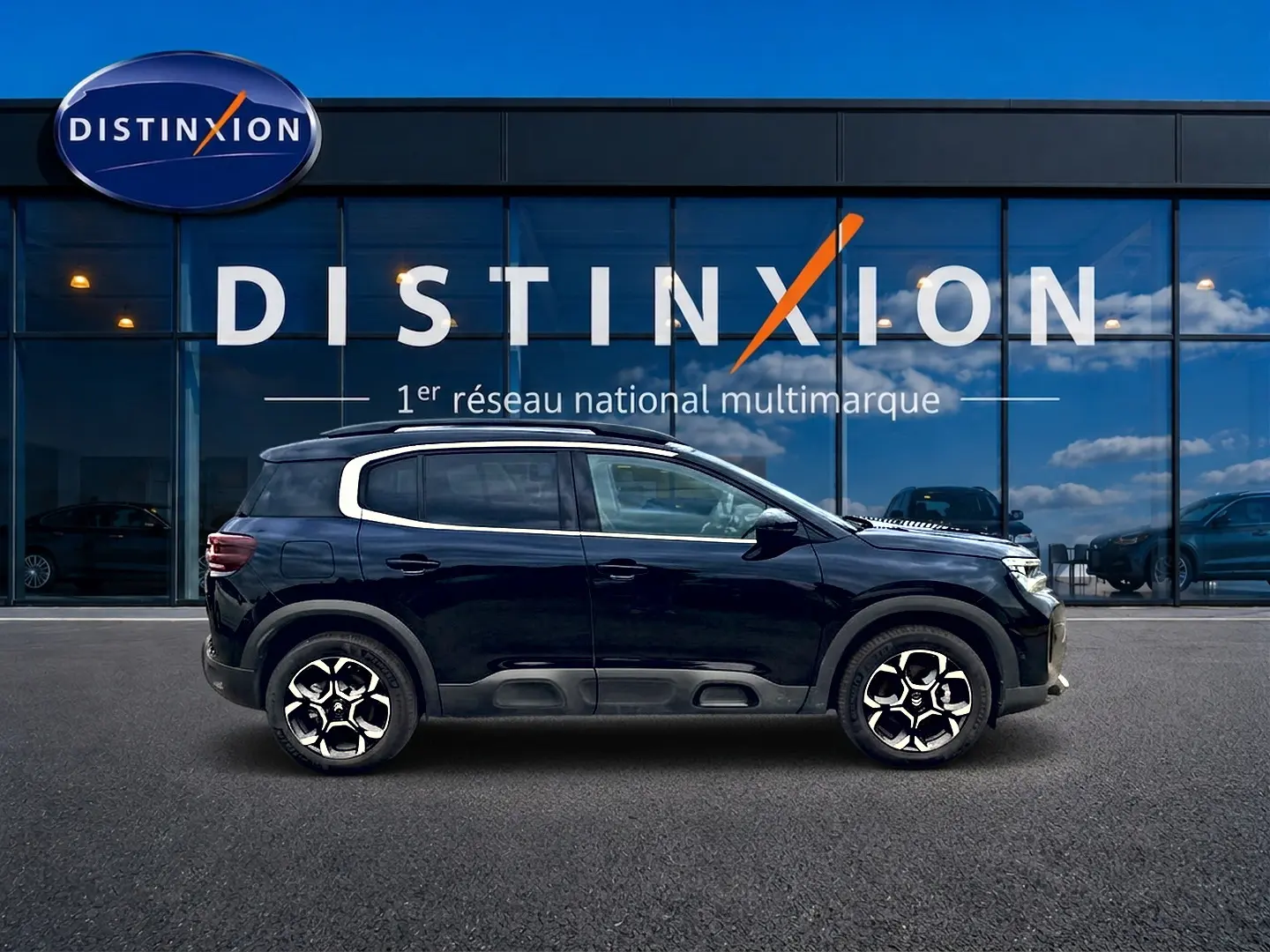 Profil droit du Citroën C5 Aircross noir 2025 avec jantes alu et barres de toit devant vitrine Distinxion.