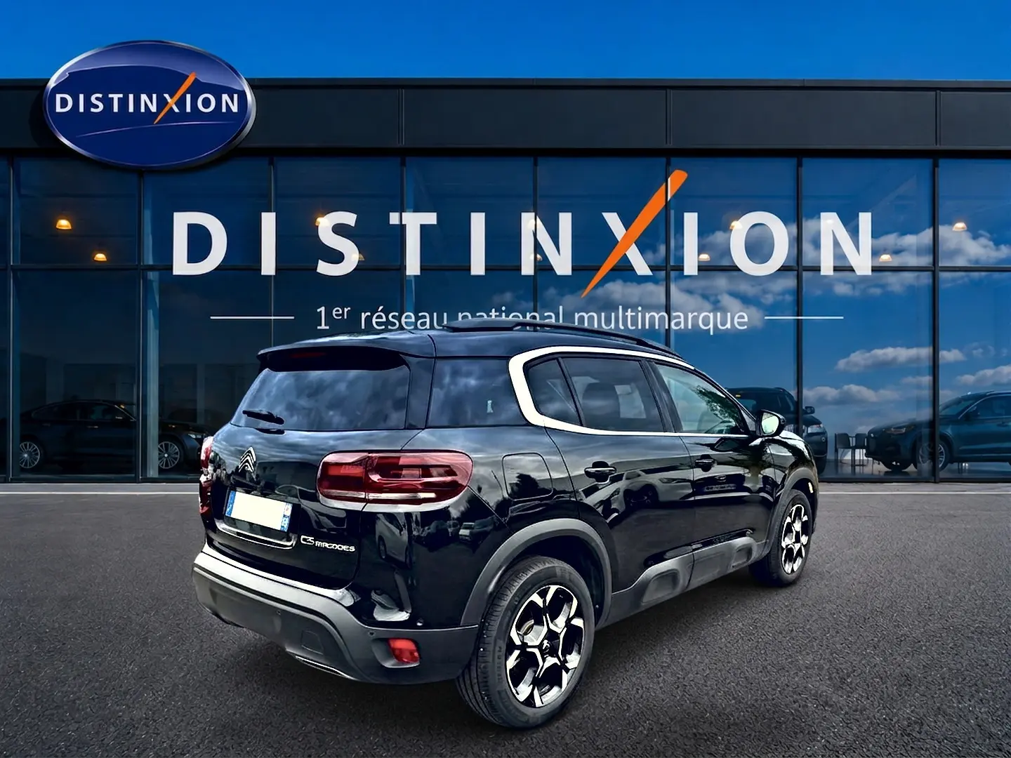 Vue 3/4 arrière droite d’un Citroën C5 Aircross noir avec jantes alu et vitres arrière teintées devant un showroom Distinxion.