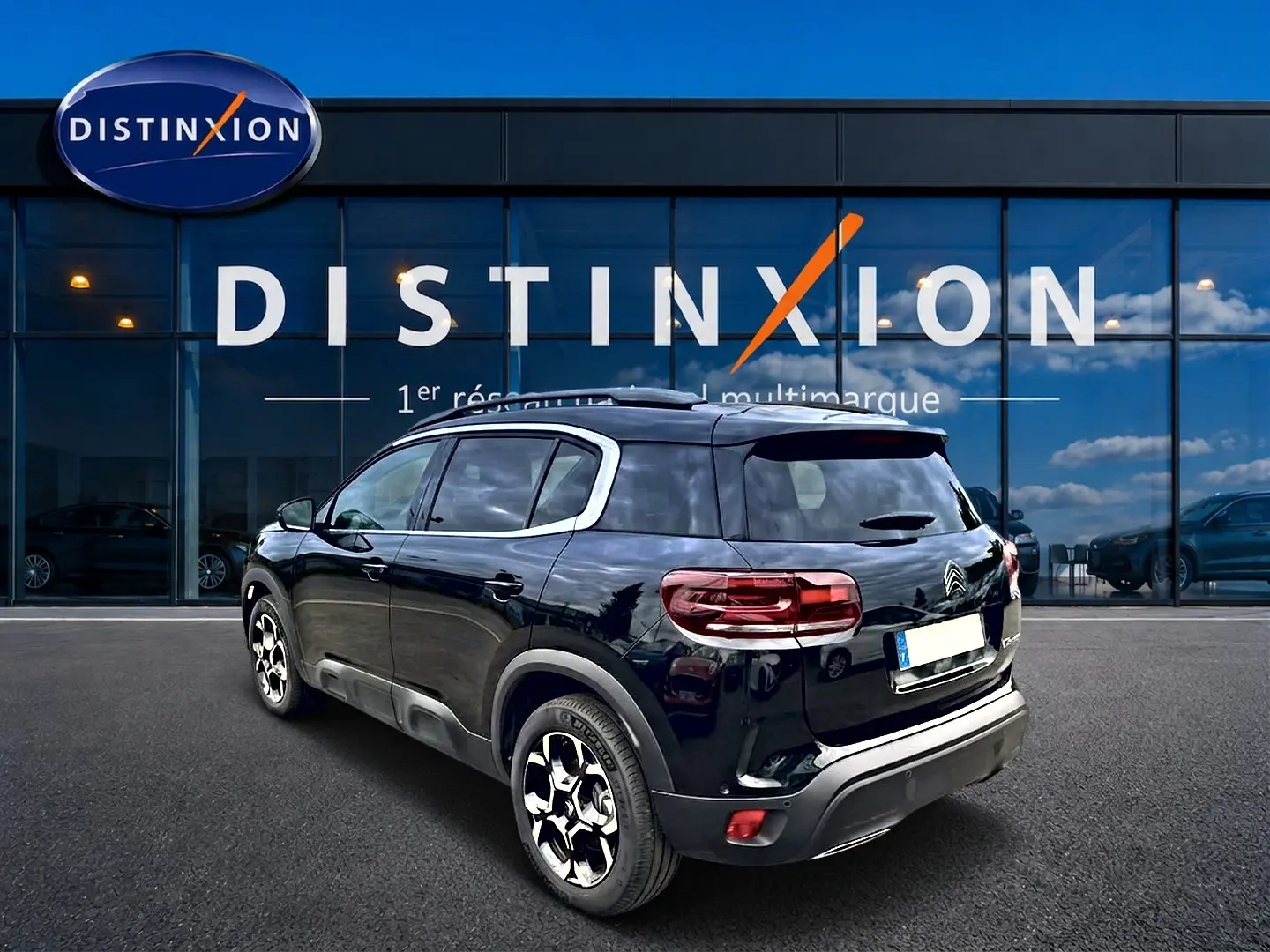 Vue 3/4 arrière droite du Citroën C5 Aircross noir 2025 avec jantes alu et barres de toit visibles.