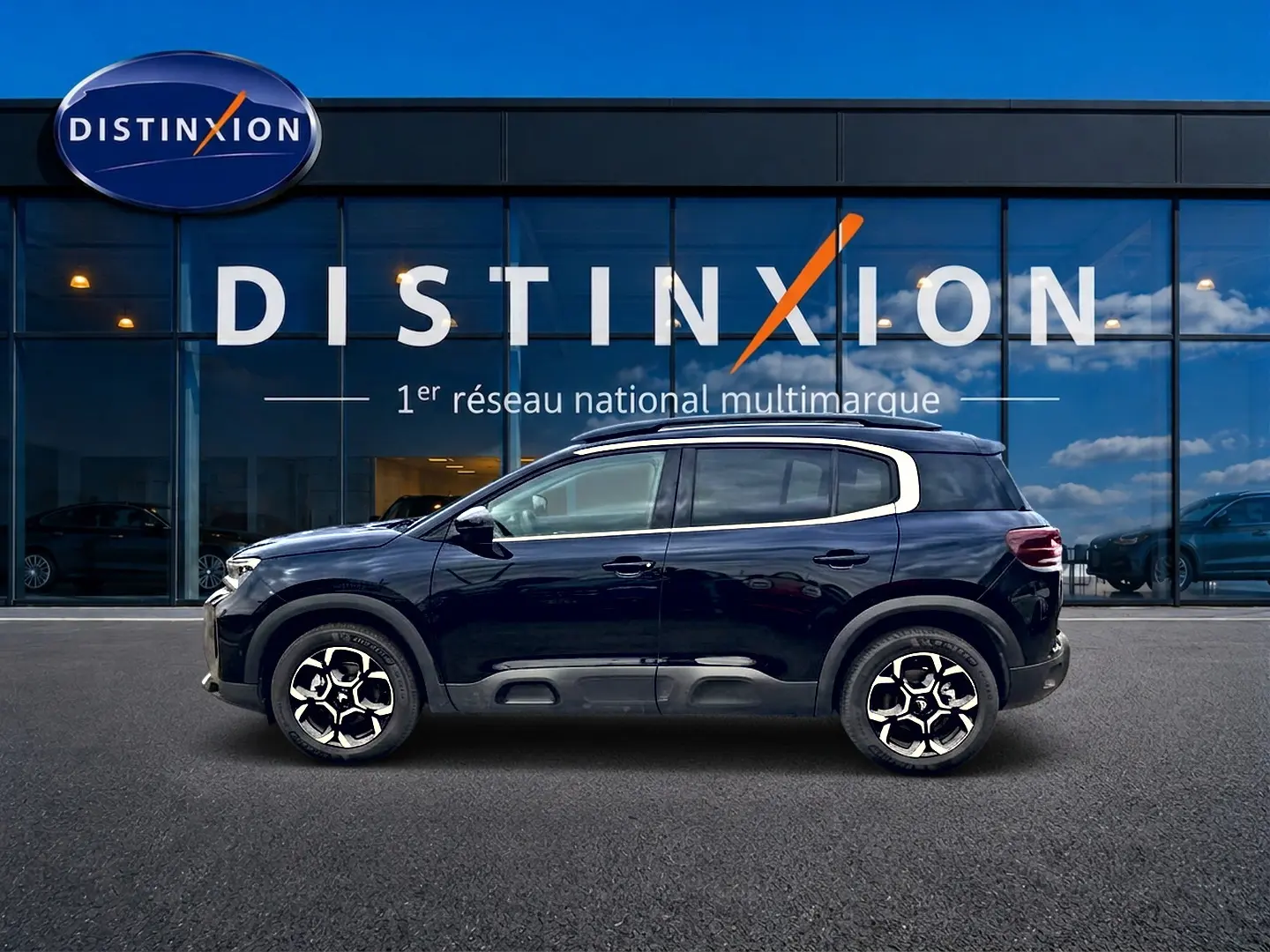 Profil côté gauche d'un Citroën C5 Aircross noir 2025 devant une vitrine avec logo Distinxion.