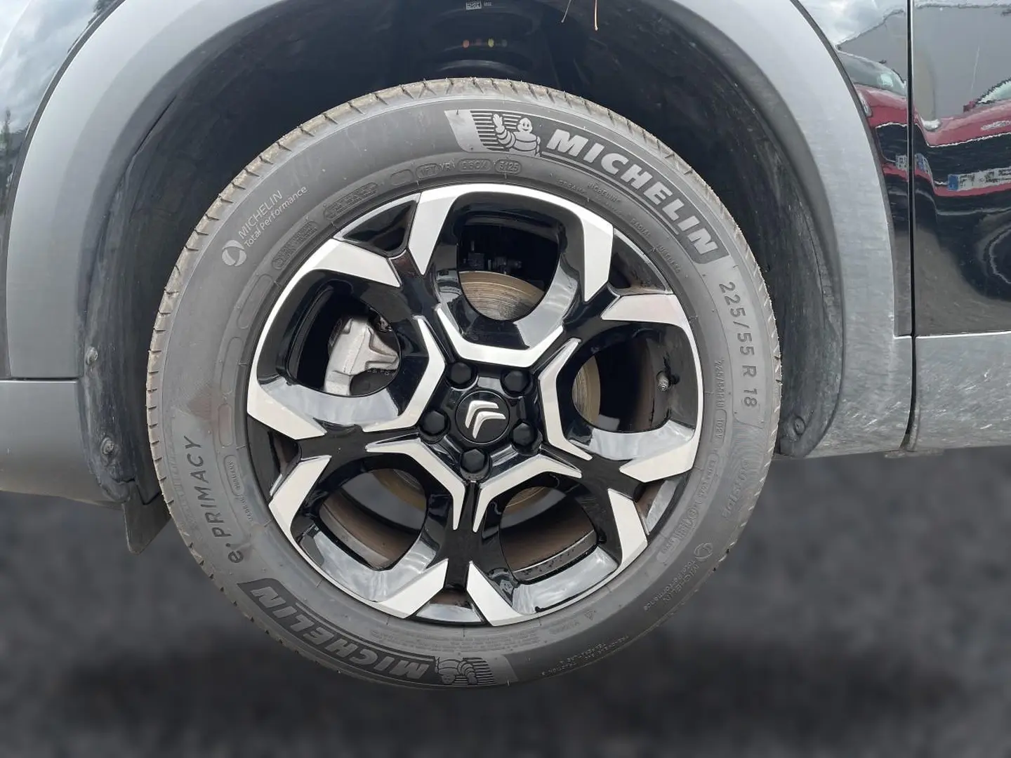 Gros plan sur la jante alu noire et argentée avec logo Citroën d’un Citroën C5 Aircross noir, vue côté avant droit.