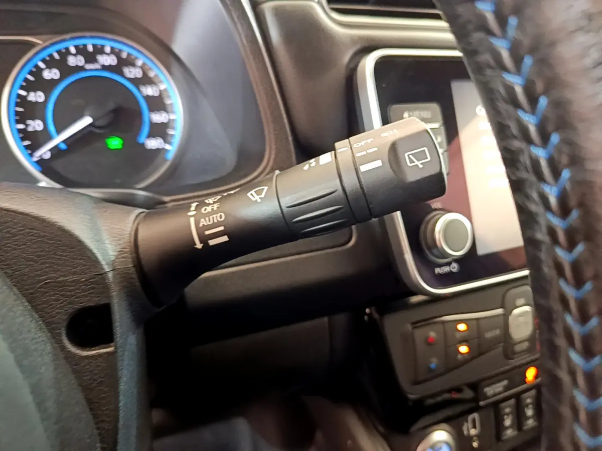 Gros plan sur la commande d'essuie-glace à gauche du volant cuir bleu sur tableau de bord Nissan Leaf blanc 2020.