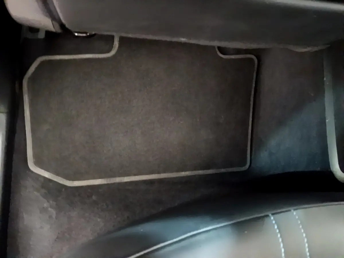 Tapis de sol noir avec surpiqûres blanches côté passager avant d'une Nissan Leaf blanche 2020.